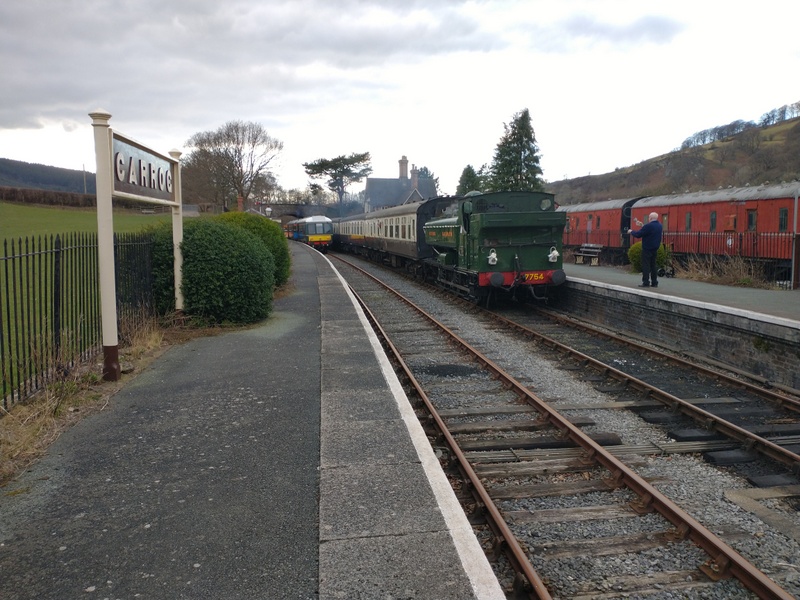 Class 108: Being passed by a steam-hauled wedding charter hauled by Pannier Tank no. 7754 at Carrog on 15/03/25